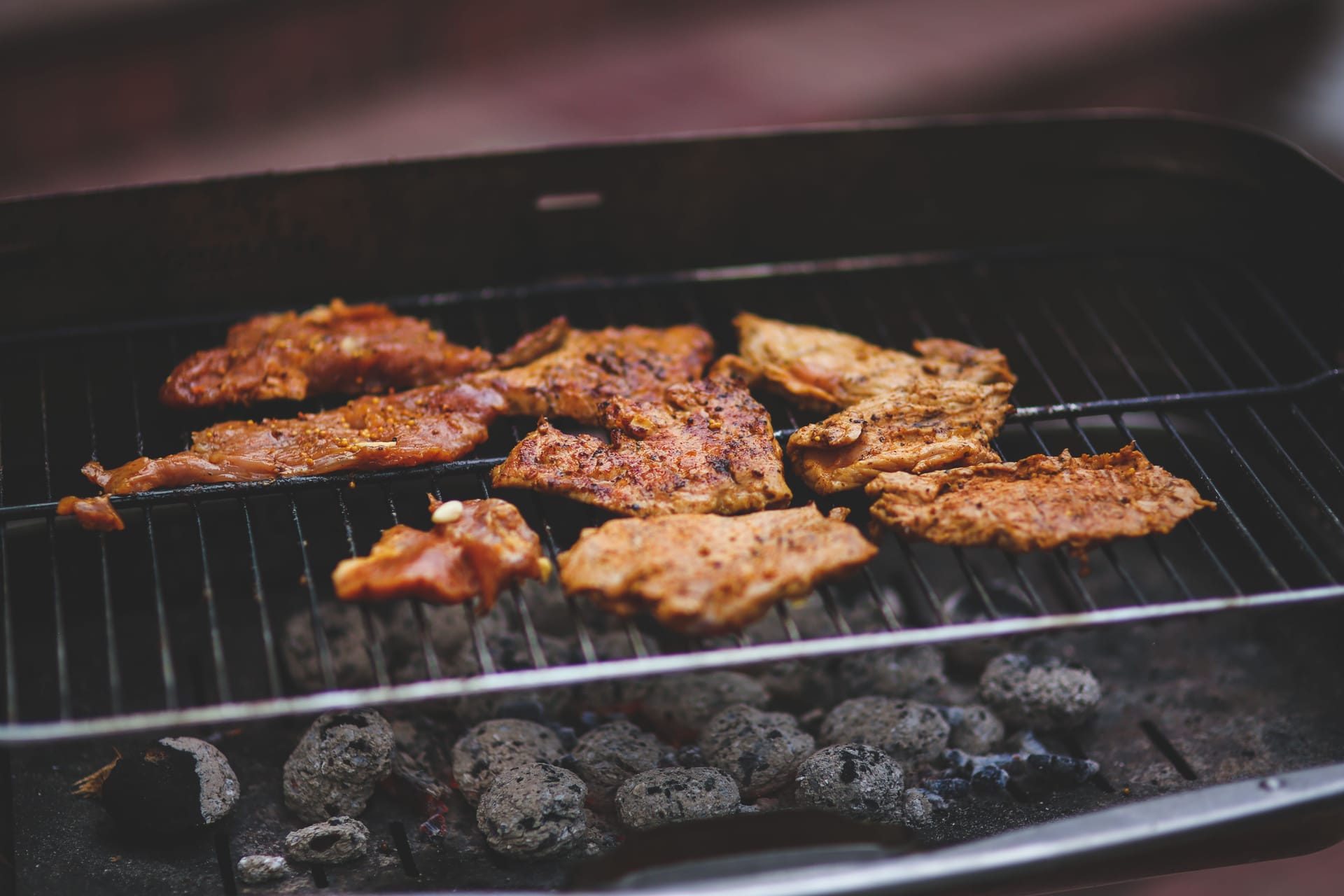 Pulizia della griglia di un barbecue con sgrassatore e spazzola per rimuovere grasso e residui di cottura.